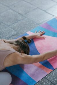 A woman stretching in a yoga pose on a vibrant mat indoors, promoting calm and fitness.